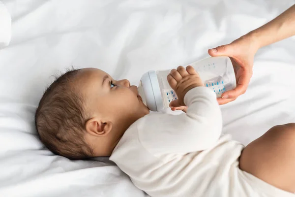 Cute little African American child drinking from baby bottle — Stock Photo, Image