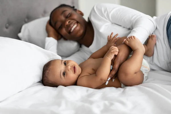 Αφρο-Αμερικανίδα μαμά ξαπλωμένη στο κρεβάτι με το γλυκό της μωρό — Φωτογραφία Αρχείου