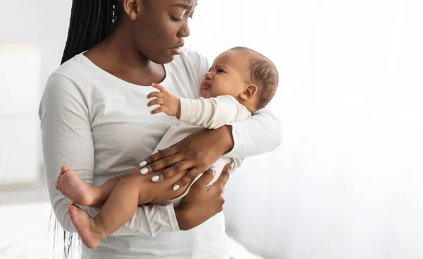 Svart mor håller gråt baby med kolik på händerna — Stockfoto