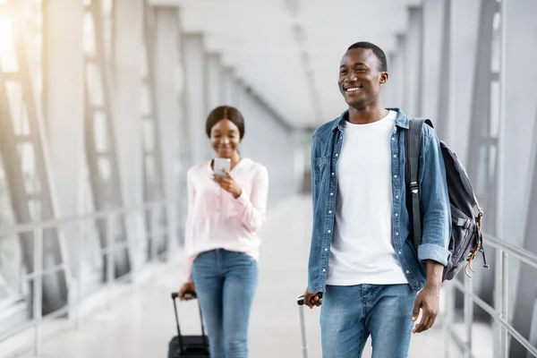 Viajar en avión. Gente negra sonriente feliz caminando con maletas en la terminal del aeropuerto — Foto de Stock