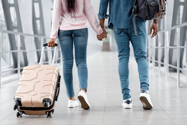 Prêt pour les vacances. Couple noir tenant la main tout en marchant dans l'aéroport, recadré — Photo