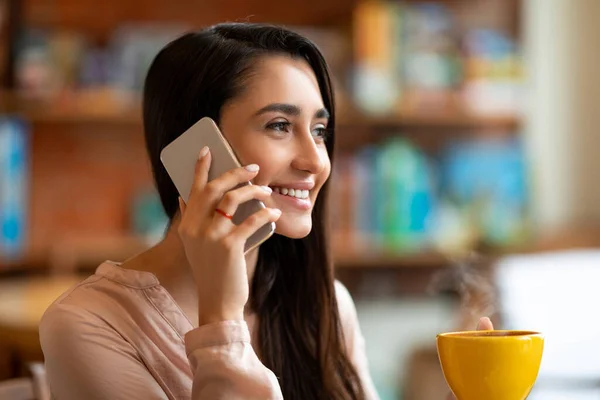 Modern cep telefonuyla konuşan heyecanlı Arap kadın kahve içerken ve kafede vakit geçirirken, boşluğu kopyalıyor. — Stok fotoğraf