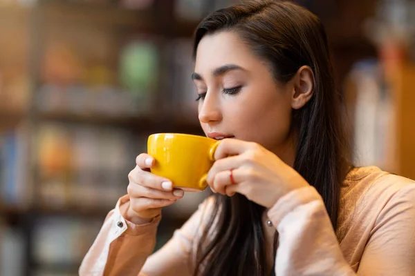 Tijd voor koffie. zorgeloze arabische dame zittend in cafe, met een mok warme drank en genietend van het aroma van koffie — Stockfoto