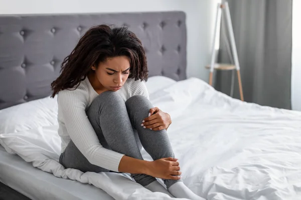 Depressieve zwarte dame zitten op bed alleen en zwak van streek — Stockfoto