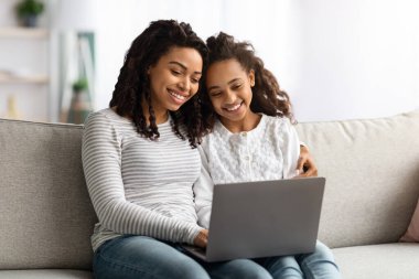 Mutlu Afro-Amerikan annesi ve çocuğu birlikte dizüstü bilgisayar kullanıyor.