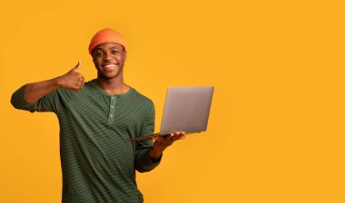 Uzak Çalışma Fırsatları. Siyah hippi dizüstü bilgisayar tutuyor ve başparmağını gösteriyor.