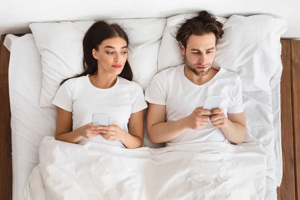 Femme regardant dans les petits amis téléphone cellulaire alors qu'il textos dans la chambre — Photo