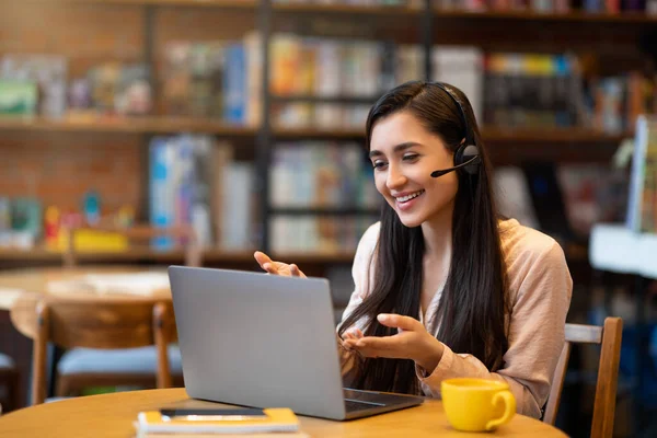 Tutoria online. Tutor latin fêmea feliz que ensina a língua extrangeira através da videoconferência, sentada no café, espaço livre — Fotografia de Stock