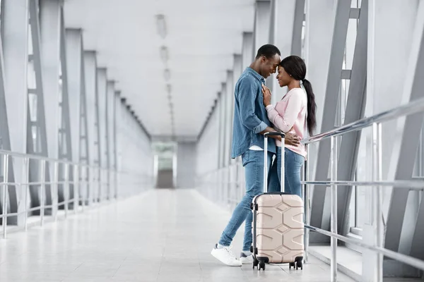 Viaje de luna de miel. Retrato de románticos recién casados negros abrazándose en la terminal del aeropuerto — Foto de Stock