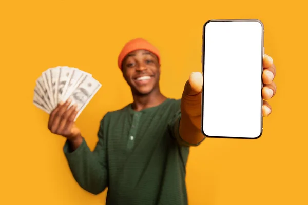 Happy Black Hipster Guy Pokazuje smartfon z pustym ekranem i trzymając pieniądze — Zdjęcie stockowe