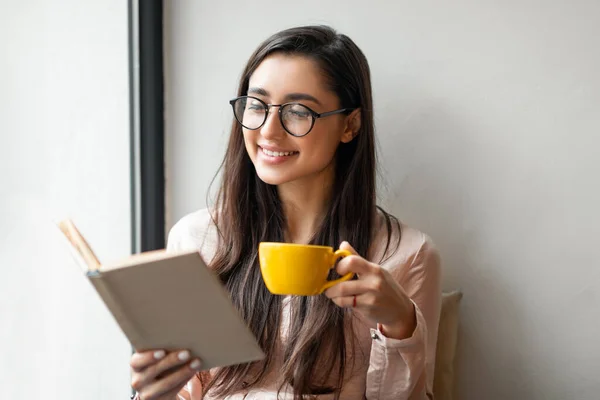 お茶を飲みながらお気に入りの本を読みながら、ウィンドウの近くのカフェで休憩、空のスペース — ストック写真