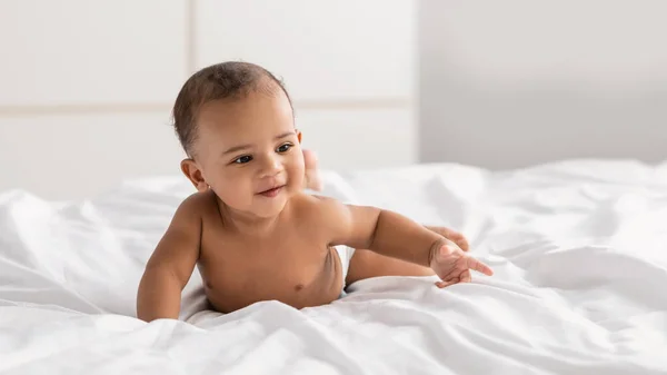 Curioso adorável menino afro-americano deitado na cama — Fotografia de Stock