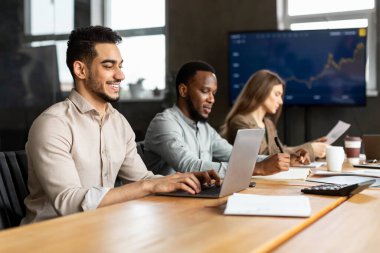 Gülümseyen erkek yönetici dizüstü bilgisayar kullanıyor, klavyede yazıyor.