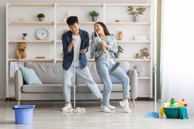 Komik Asyalı çift daireleri temizlerken şarkı söylüyor.