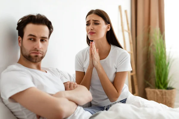 Ongelukkig vrouw pleiten beledigd onverschillig echtgenoot voor vergeving Indoor — Stockfoto