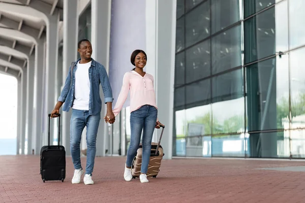 Viaje de vacaciones. Retrato de feliz pareja africana caminando con maletas cerca del aeropuerto — Foto de Stock