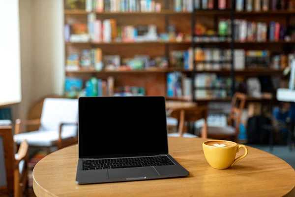 Locul de muncă în cafenea. Computer laptop cu ecran alb negru și cană de cafea pe masă de lemn. Mockup — Fotografie, imagine de stoc