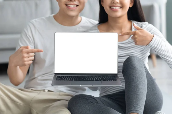 Cropped of sporty asian couple showing laptop with blank screen