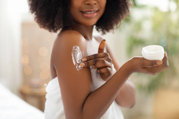 Vista recortada da jovem negra aplicando creme em seu corpo, mimando sua pele após o banho em casa, close-up — Fotografia de Stock