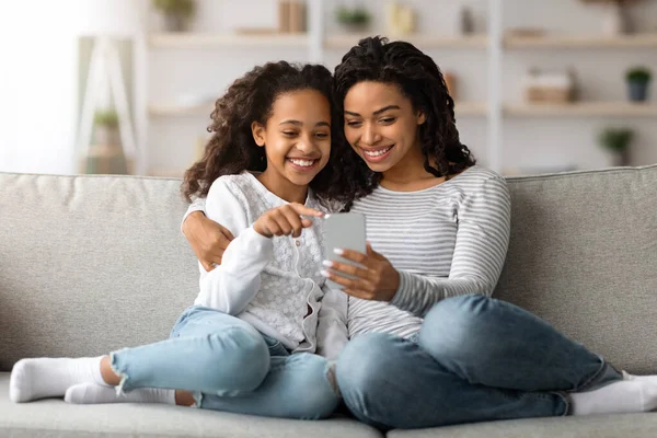 Glada afrikanska amerikanska mor och dotter använder smartphone tillsammans — Stockfoto