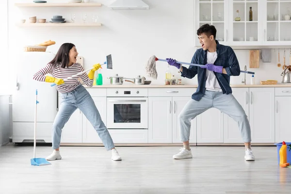 Gek aziatisch jong paar hebben plezier tijdens het schoonmaken appartement — Stockfoto