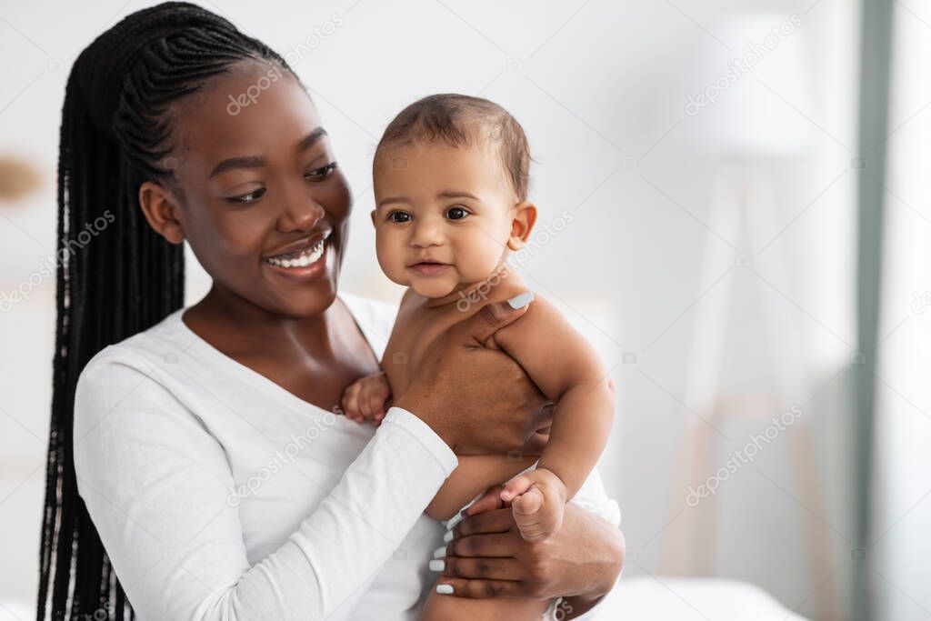 African American nanny hugging her cute infant and posing