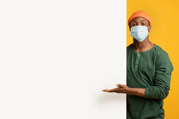 Black Millennial Man In Medical Face Mask Peka på vit Annons Board — Stockfoto