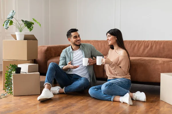 Счастливые мужчина и женщина пьют кофе сидя на полу — стоковое фото