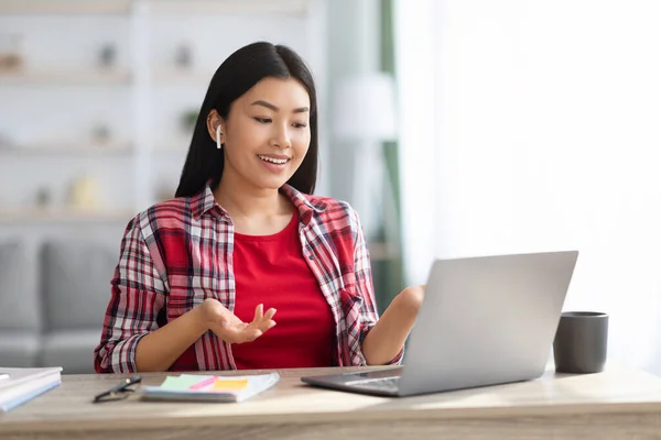 Online communicatie. Vrolijke Aziatische dame met laptop en Airpods maken van video call — Stockfoto