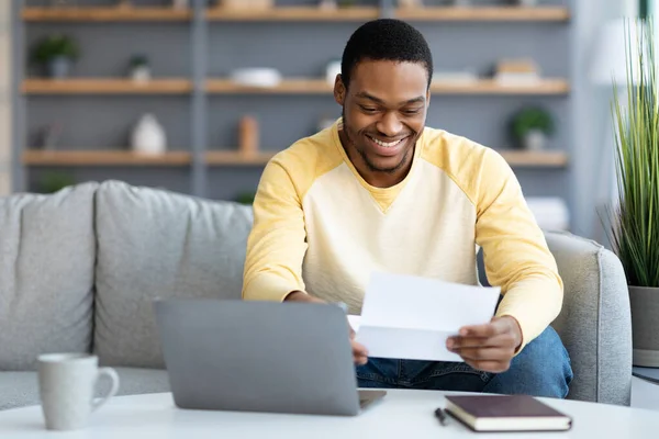 Glimlachende Afrikaan amerikaanse man lezen brief thuis — Stockfoto