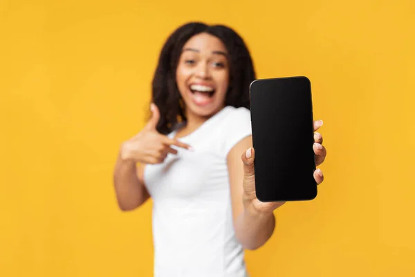 Geweldige boodschap. Verrast Afrikaans-Amerikaanse dame toont smartphone met blanco scherm over gele achtergrond — Stockfoto