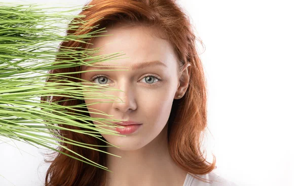 Portret van roodharige vrouw poseren met groen gras, witte achtergrond — Stockfoto