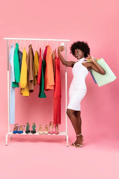 Mujer negra de compras haciendo selfie con bolsas de comprador, fondo rosa —  Fotos de Stock