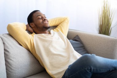 Memleketteki kanepede uzanan neşeli Afrikalı Amerikalı adam.