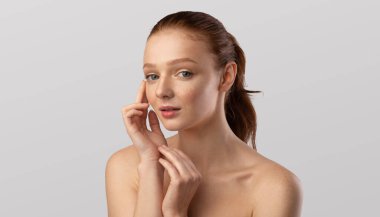 Gri Arkaplan Üzerine Cilt Bakımı Yapan Genç Kadın