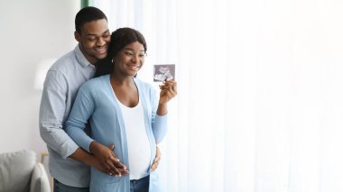 Çekici Afrikalı Amerikalı çift bebek sonogramıyla poz veriyor.