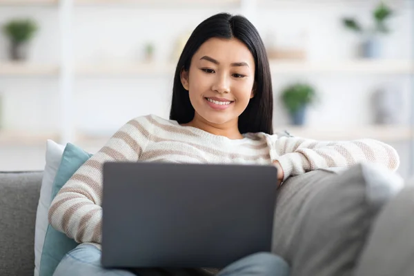 Op afstand werken. Portret van lachende jonge Aziatische dame met behulp van laptop thuis — Stockfoto