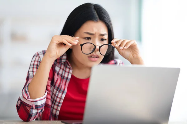 Zichtproblemen. aziatische vrouw opstijgen glazen terwijl op zoek naar laptop scherm — Stockfoto