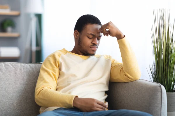 Deprimido negro chico sentado en sofá solo en casa —  Fotos de Stock