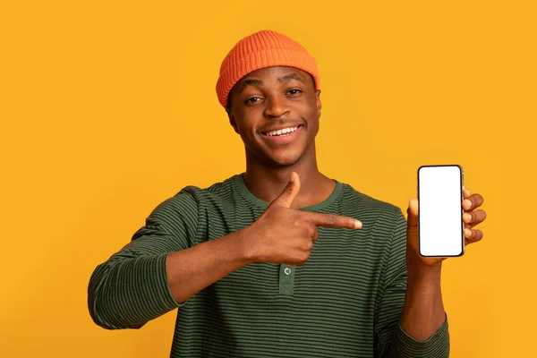 Feliz negro Hipster Guy sosteniendo y señalando en el teléfono inteligente con pantalla blanca —  Fotos de Stock