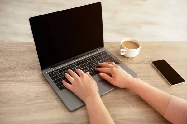 Conceptul de muncă la distanță. Femeie de nerecunoscut tastând pe tastatura laptopului, stând la birou cu o ceașcă de cafea și smartphone — Fotografie, imagine de stoc