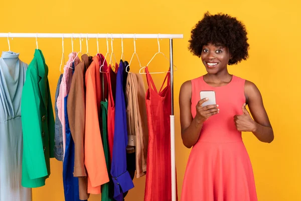 Preto Shopaholic mulher compras no telefone gestando polegares-up no estúdio — Fotografia de Stock