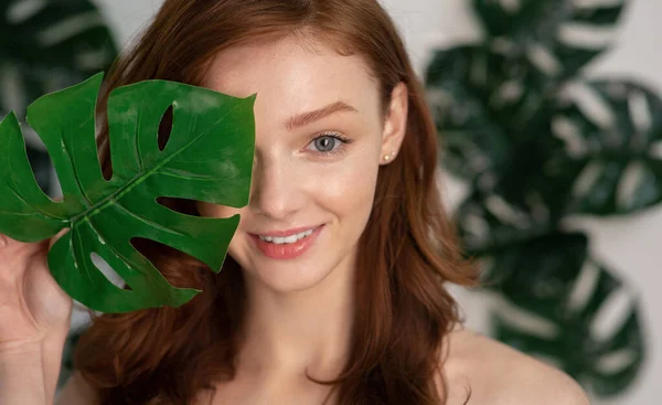 Chica posando con hoja de monstera sobre fondo con hojas tropicales — Foto de Stock