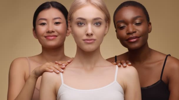 Amitié féminine et connexion. Trois heureuses dames multiethniques posant sur fond de studio beige, câlinant ensemble — Video