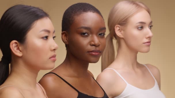 Ernstige jonge Afrikaanse Amerikaanse vrouw op zoek naar camera, poseren met aziatische en Kaukasische dames vrienden, beige achtergrond — Stockvideo