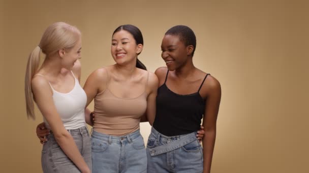 Tres mujeres jóvenes diversas abrazando y riendo juntas, mirando alegremente a un lado en el espacio vacío, cámara lenta — Vídeos de Stock