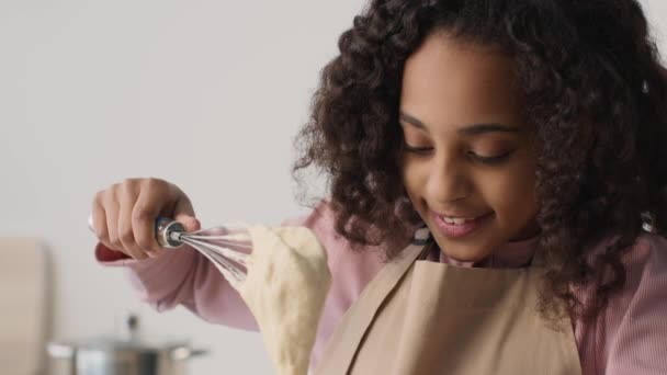 Detailní záběr portrét malé africké americké dívky sledující její čerstvé těsto, těší proces vaření v kuchyni — Stock video