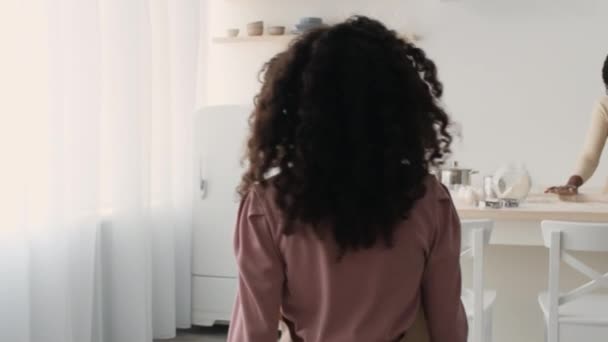 Ακολουθήστε πλάνο του μικρού Αφροαμερικανού κοριτσιού που έρχονται στη μητέρα της στην κουζίνα και να βοηθήσει με το ψήσιμο, εντοπισμό shot — Αρχείο Βίντεο