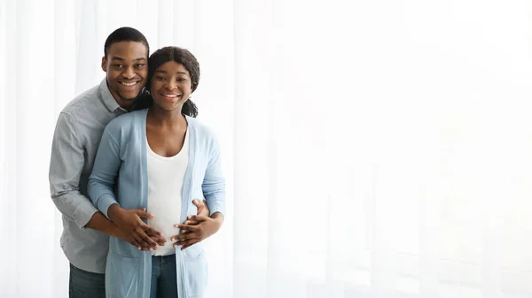 Счастливая черная пара ждет ребенка, позируя на белом фоне — стоковое фото