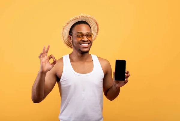 Gondtalan afro-amerikai srác a nyári viselet gazdaság smartphone-val mockup, mutató rendben gesztus — Stock Fotó